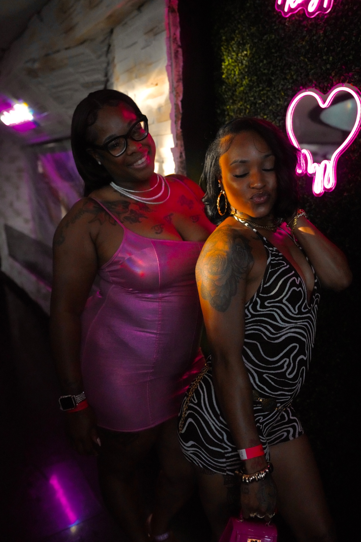 Friends posing beside the neon heart inside Cross Ultra Lounge